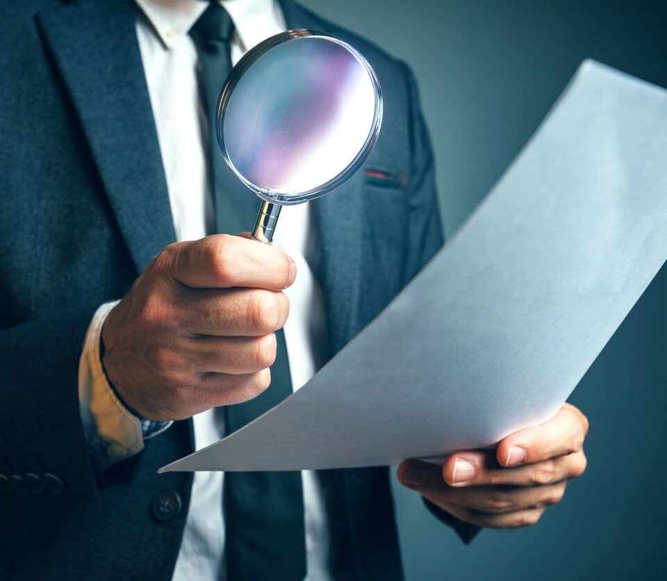 Man with a magnifying glass, representing in-depth, careful research.